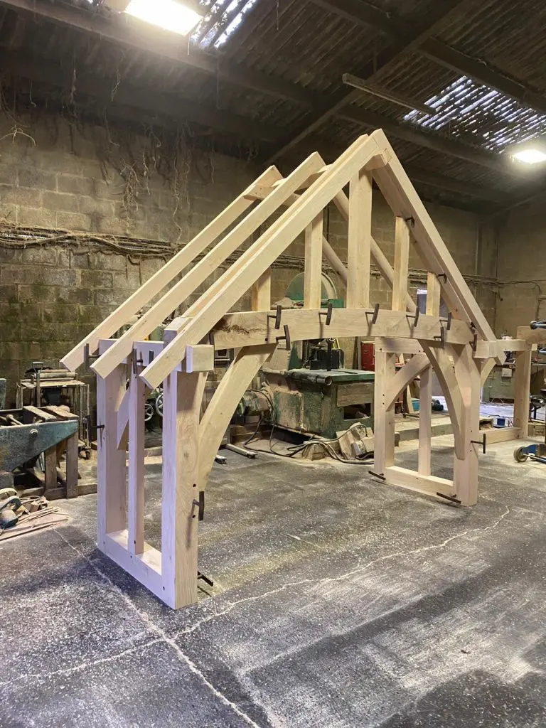 Custom cut fresh sawn oak beams used to create a porch in a workshop ready to be fitted.