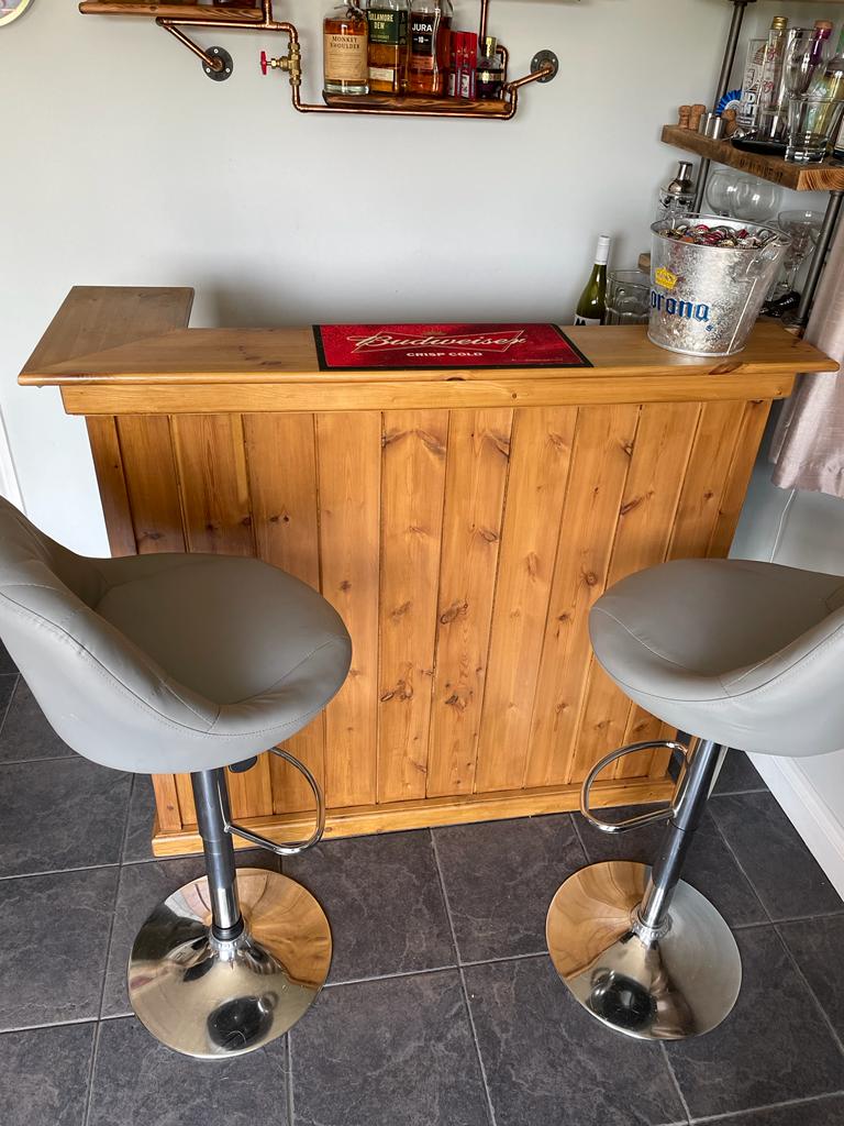 Home bar created using character grade v tongue and groove cladding and kiln dried oak boards with bar stools in front of it and shelving created out of kiln dried oak boards behind it.