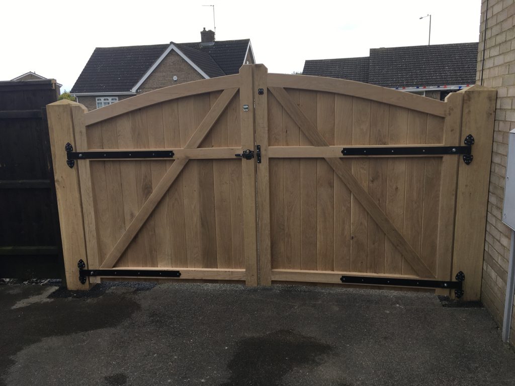 Closeboard curved top oak driveway gates with planed posts on either side to create property edging.