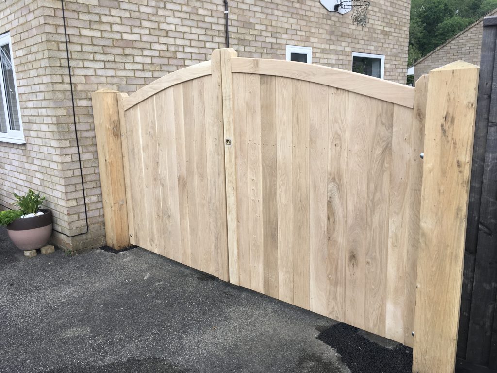 Closeboard curved top oak driveway gates with planed posts on either side to create property edging.