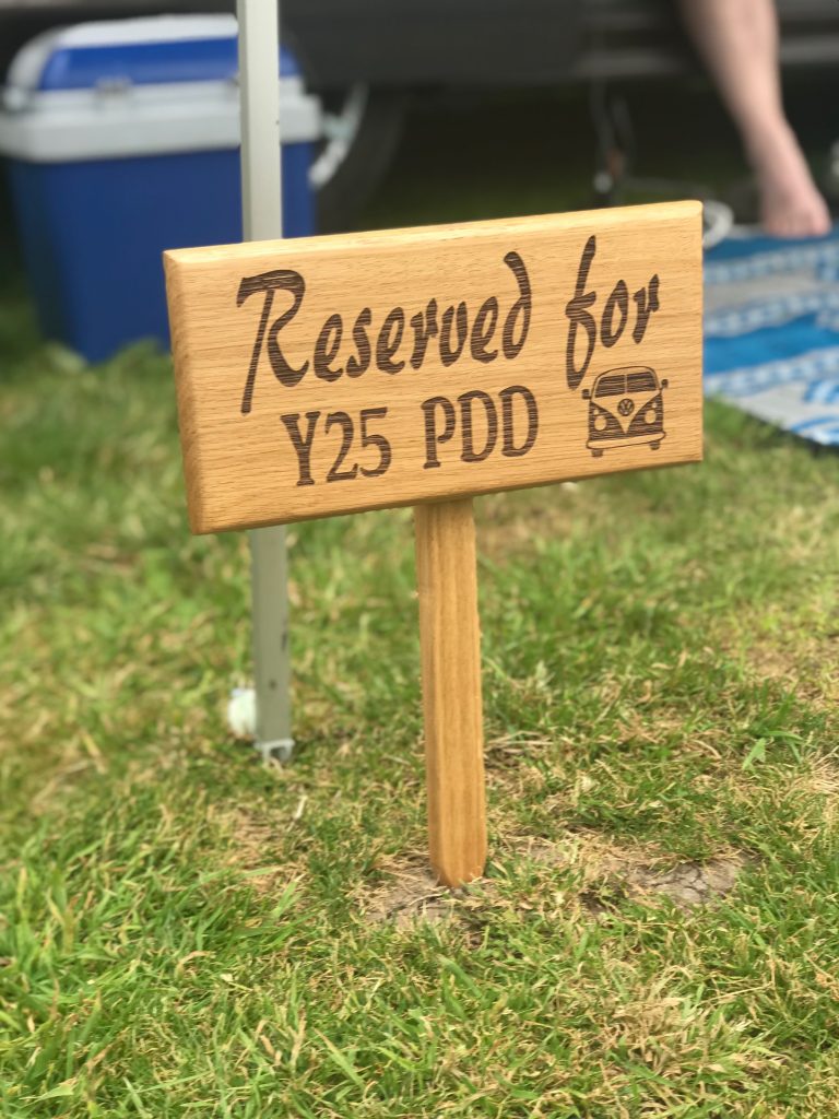 A wooden sign in the grass made out of kiln dried oak