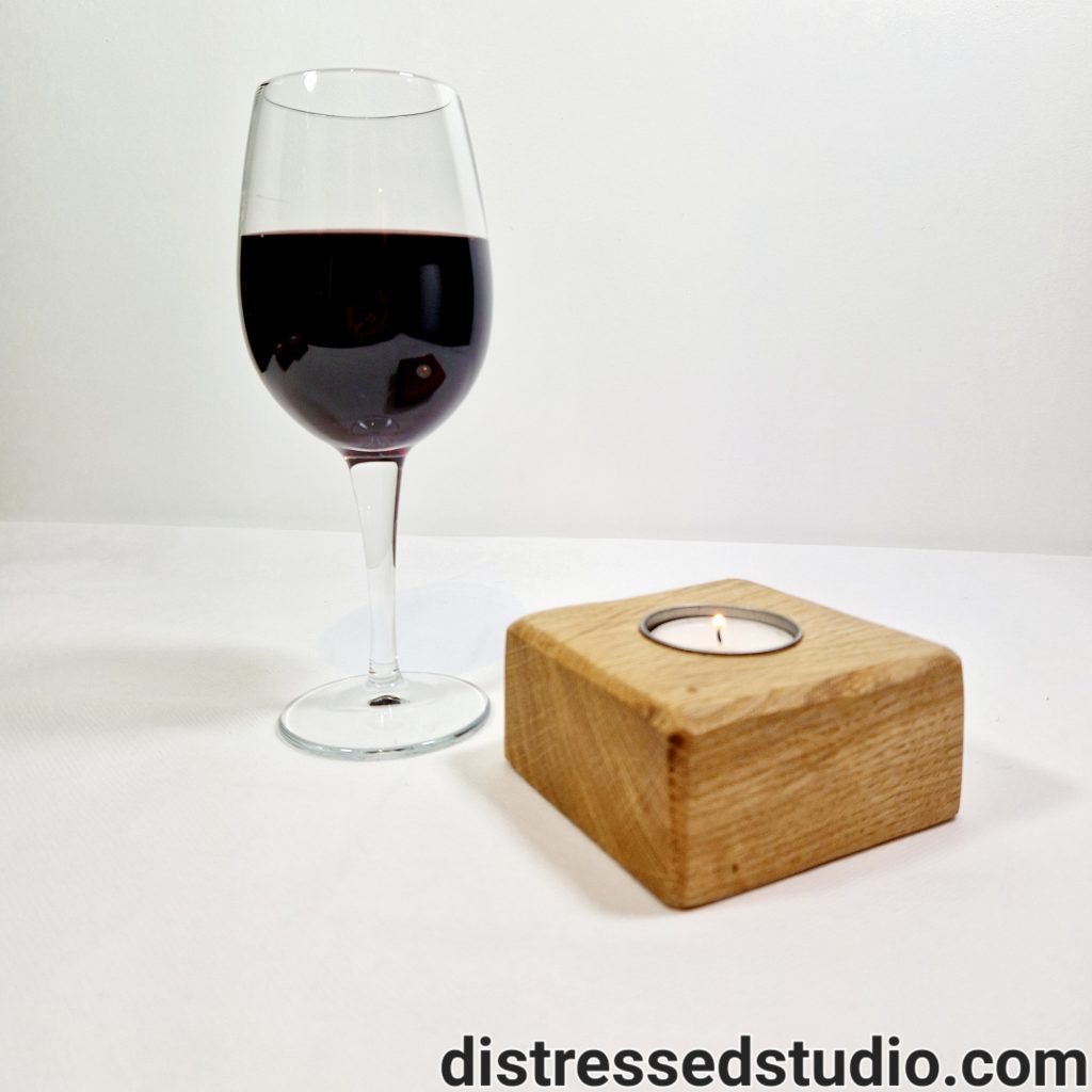 An Oak Candle Holder next to a glass of wine