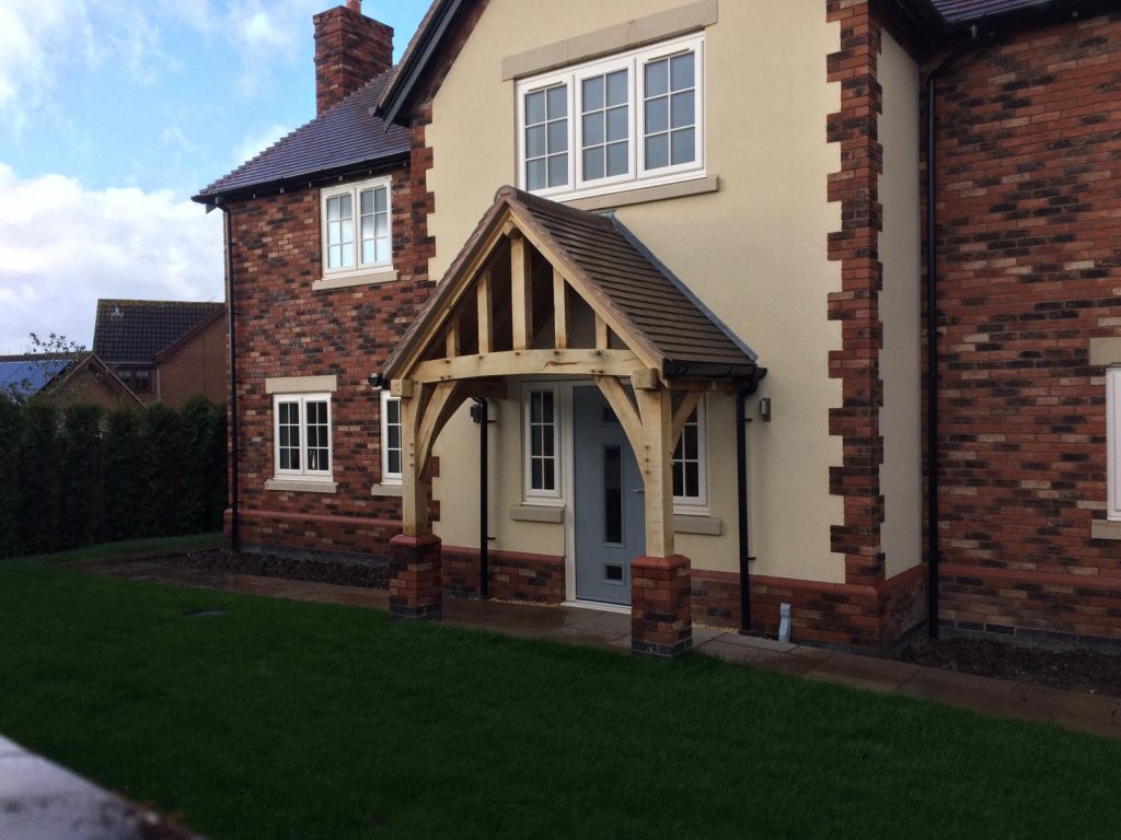 A porch made out of custom cut fresh sawn green oak from UK Timber to cover the front doorway of a modern house