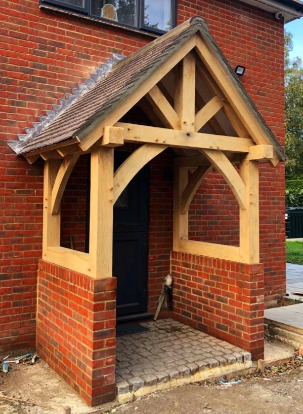 A porch made out of custom cut fresh sawn green oak beams in front of a brick house
