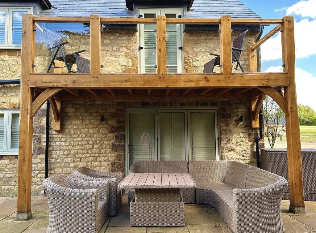 oak beams used to create a glass protected balcony overlooking a back garden