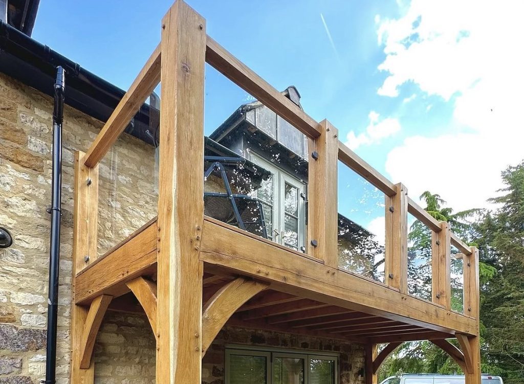 oak beams used to create a glass protected balcony overlooking a backgarden