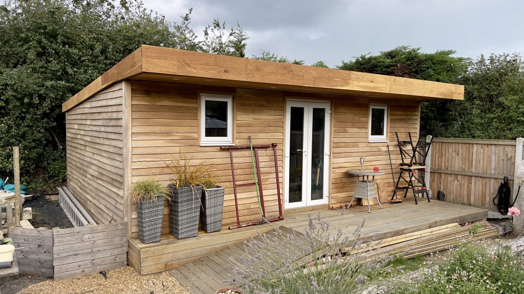 a garden room created using air dried oak beams, lightweight oak featheredge cladding and fresh sawn green oak. Lightweight Air Dried Oak Featheredge Cladding, Structural Air Dried Oak Beams, Fresh Sawn Green Oak Board, sleek trim boards to create the exterior